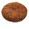A round throw cushion with an orange and red bohemian pattern.