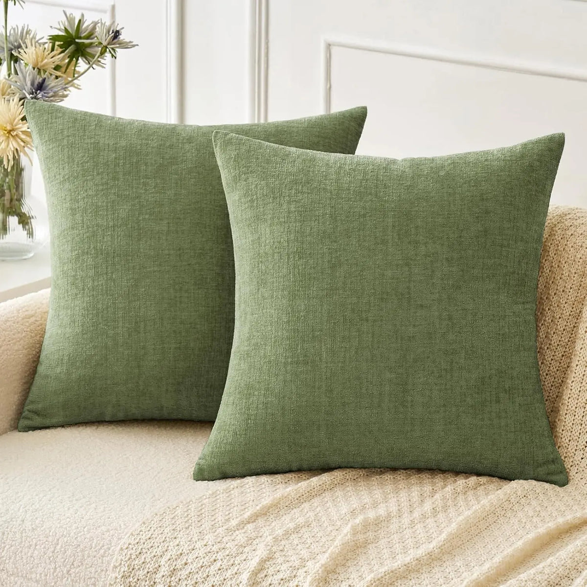 Solid olive green chenille throw pillow cover resting on a beige textured sofa cushion.