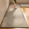 A person standing on a light gray kitchen floor mat with concentric circular patterns on a wooden floor.
