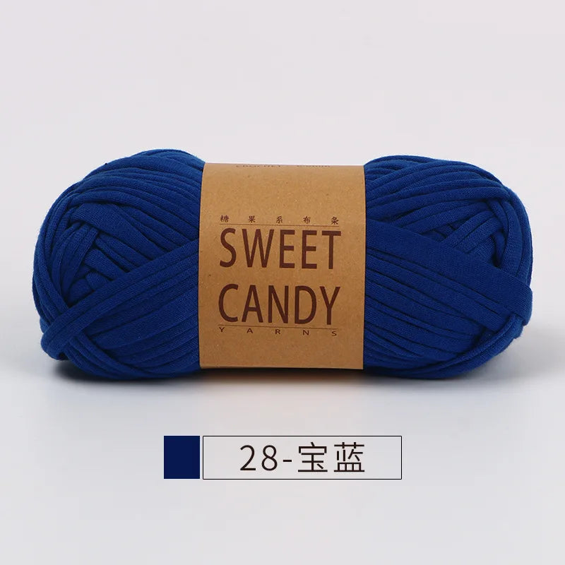 A skein of dark blue hand-dyed fabric strip yarn labeled Sweet Candy Yarns.