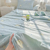A light blue quilt blanket with a pastoral print featuring small white animals and stars, displayed on a bed.
