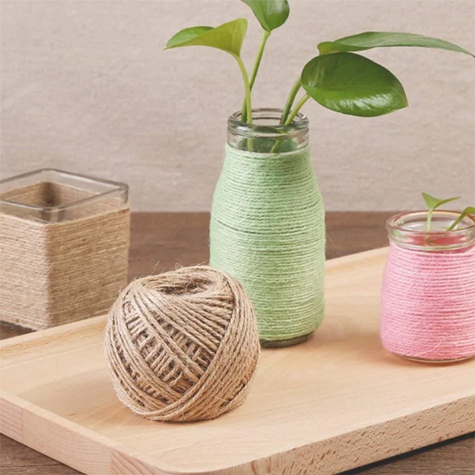 A glass jar filled with green twine next to a ball of natural jute twine on a wooden cutting board.