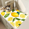 A yellow and green lemon printed non-slip dish drying mat placed next to a kitchen appliance.