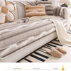 Anti-slip plush sofa cover in gray stripes with decorative pillows and a striped rug.