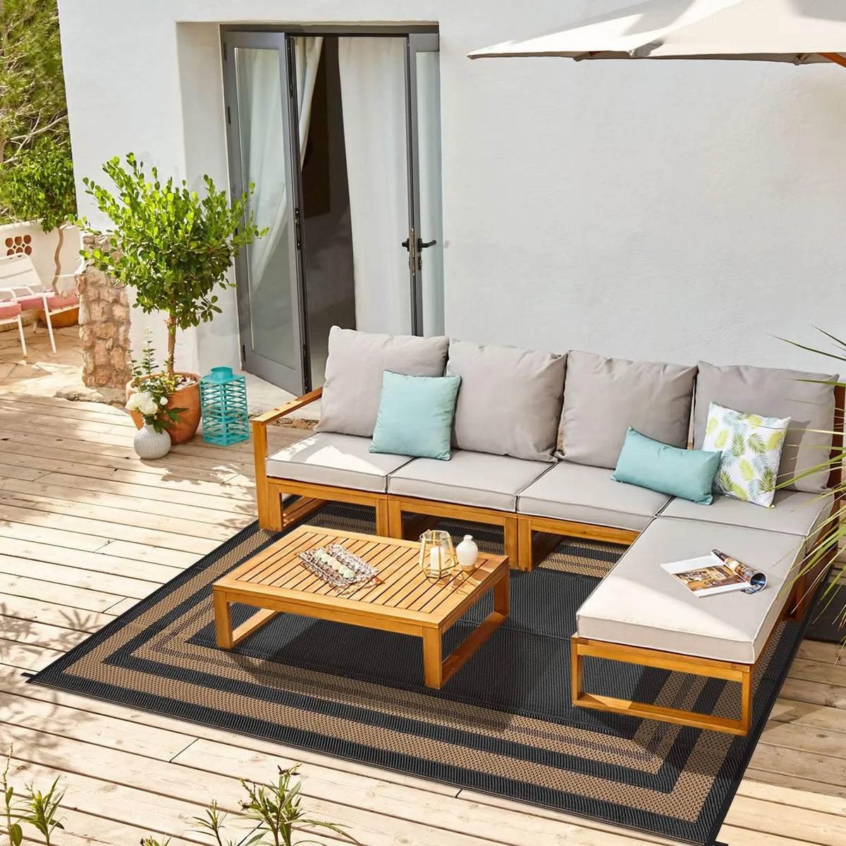 A reversible outdoor patio rug featuring a wooden frame and dark mat, placed on a wooden deck.