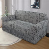 A gray pleated fabric sofa cover displayed on a light-colored rug in a living room setting.