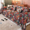 A romantic floral jacquard sofa throw blanket draped over a sofa with decorative pillows and a wooden cabinet in a softly lit