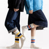 A pair of men's retro striped crew socks worn by a person, featuring ribbed athletic style.