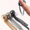 A hand holds a set of adjustable metal shirt shorteners featuring gold and silver chains.