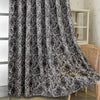 Blackout curtains featuring a tree bark pattern in black and white fabric hanging indoors.