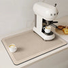 A white espresso machine is placed on a beige kitchen drain mat with a cup of coffee and some toast.