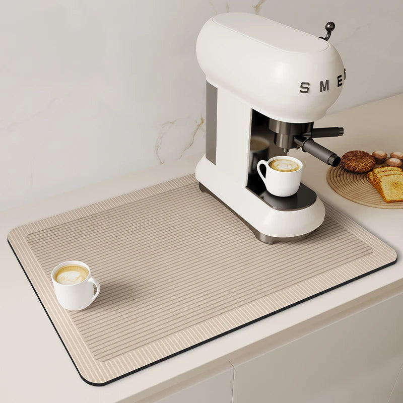 A white espresso machine is placed on a beige kitchen drain mat with a cup of coffee and some toast.