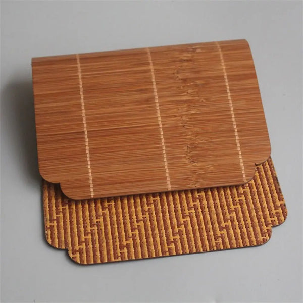 A rectangular bamboo tea mat with parallel lines, resting on a larger, intricately woven bamboo mat.