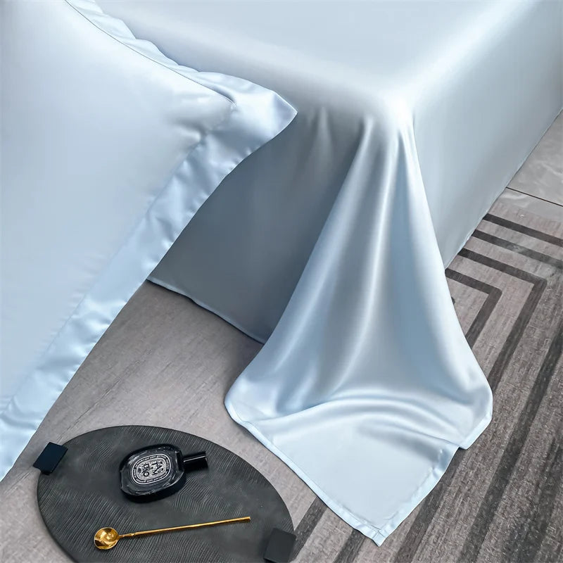 Light blue luxury bamboo flat sheets draped on a table with a gold measuring tool.