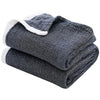 A stack of dark gray muslin throw blankets with white trim.