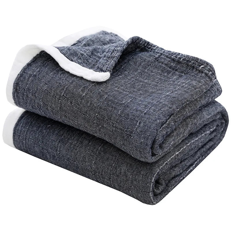 A stack of dark gray muslin throw blankets with white trim.