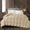 A beige quilted duvet with white pillows is displayed on a bed in a softly lit room.