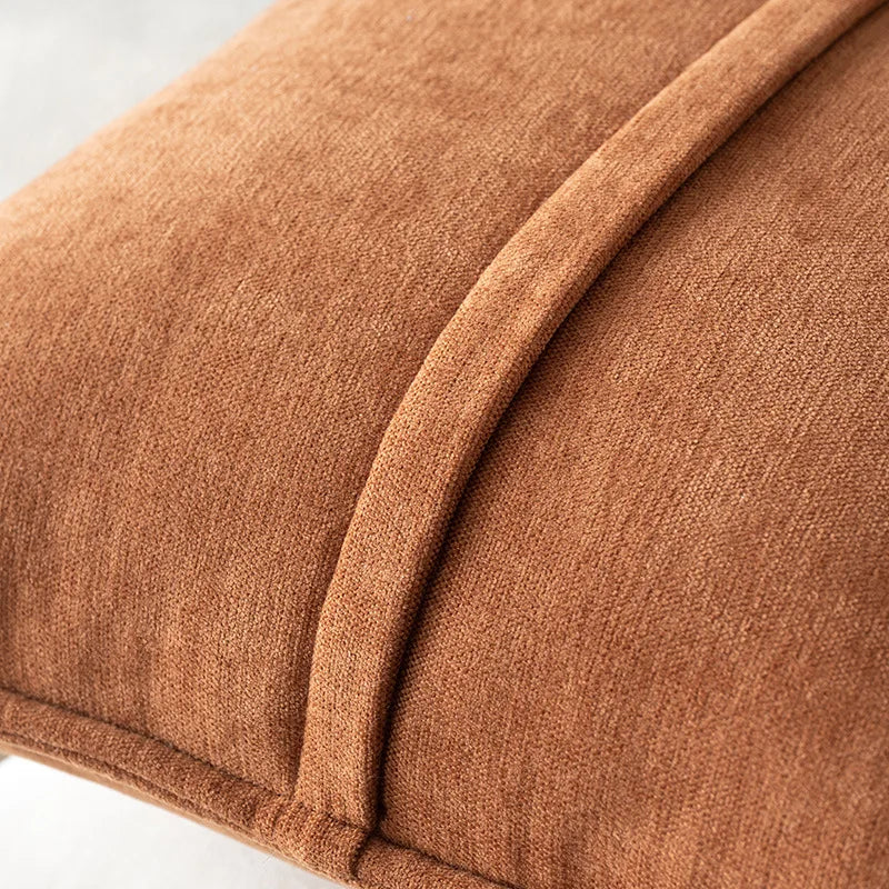 A close-up of a brown chenille throw pillow cover with a curved seam detail.
