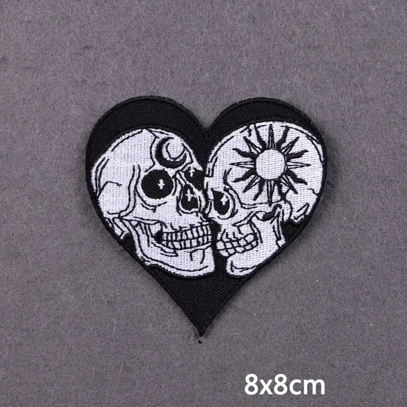 Black heart-shaped iron-on patch featuring white embroidered skulls