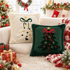A collection of embroidered Christmas tree velvet pillow covers in green and cream on a white fluffy rug.