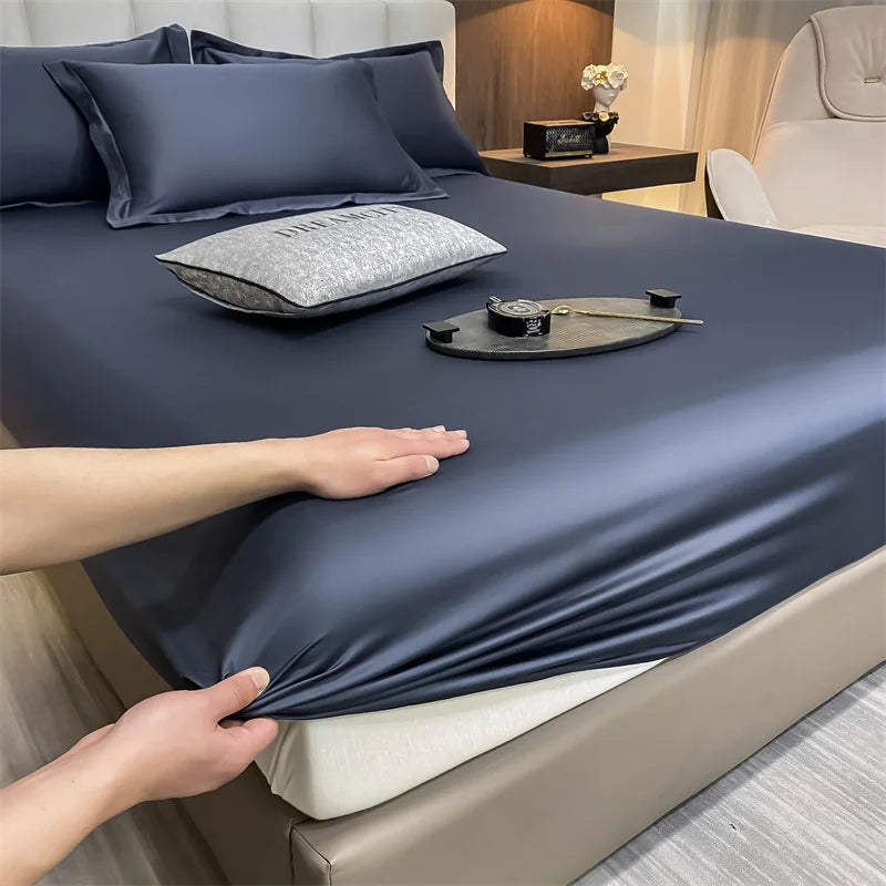 A hand is adjusting a dark blue luxury Egyptian cotton fitted bed sheet on a bed.