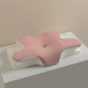 A pink ergonomic memory foam cervical pillow resting on a white surface.