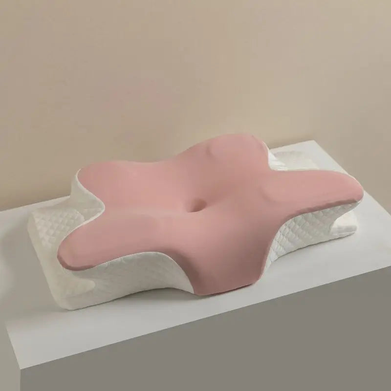 A pink ergonomic memory foam cervical pillow resting on a white surface.