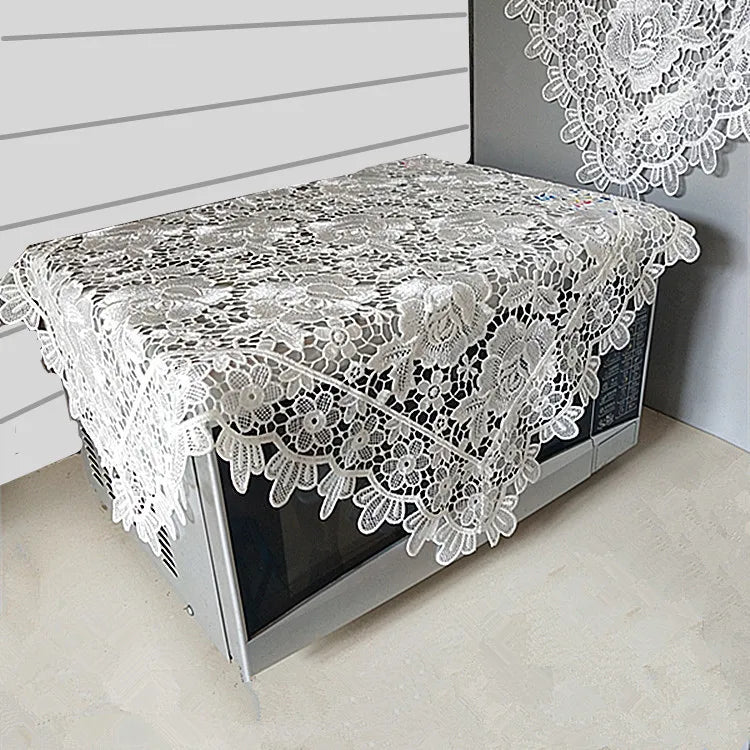 A table covered with a white floral lace tablecloth displayed in a modern setting.