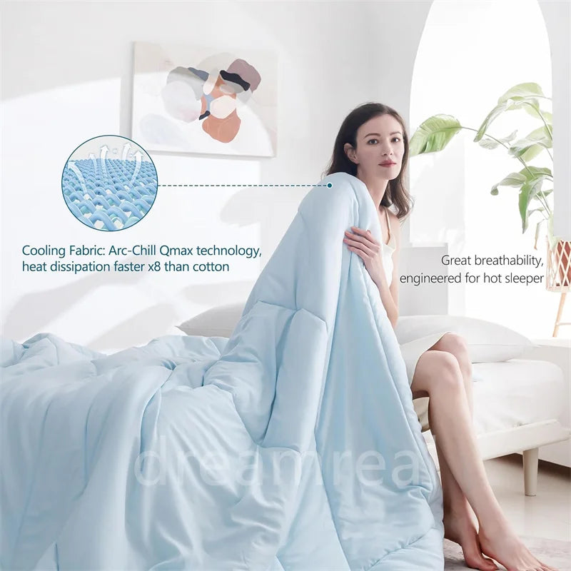A light blue reversible cooling quilt is draped on a bed, highlighting its Arc-Chill Qmax technology.
