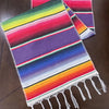 Colorful cotton Mexican sarape table runner with horizontal stripes in rainbow and purple hues