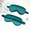 A teal silk sleep mask with a ruffled edge is displayed on a white background next to a Chanel branded box.