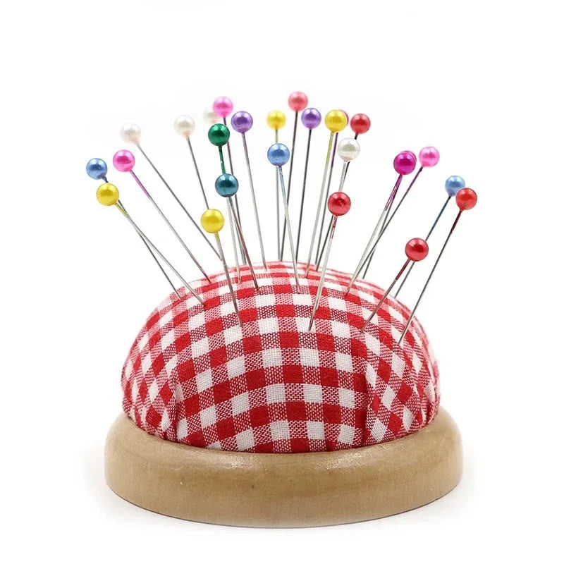 A collection of colorful pearl straight head pins arranged on a red and white checkered fabric base.