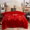 A vibrant red velvet weighted blanket displayed on a bed with white and beige pillows.