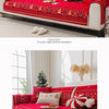 A red decorative sofa seat cover with white embroidery and festive accents displayed on a modern sofa.