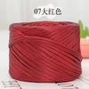 A spool of metallic red cake yarn for crafting, tightly wound and displayed on a white surface.