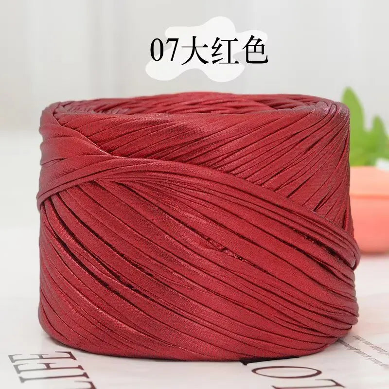A spool of metallic red cake yarn for crafting, tightly wound and displayed on a white surface.