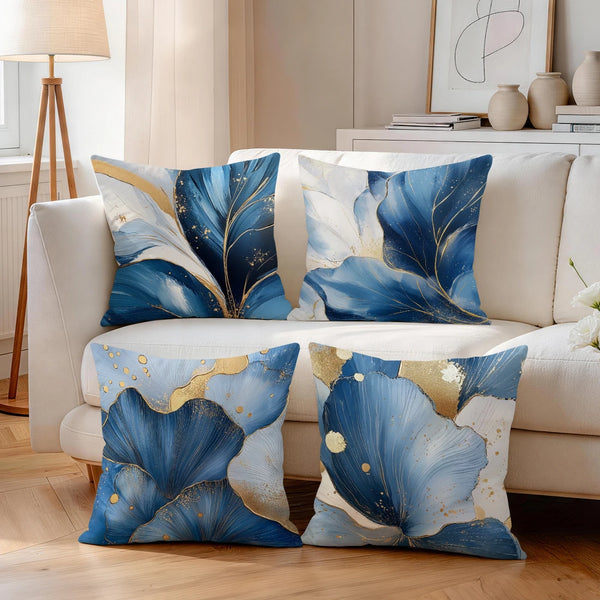 Blue and gold abstract leaf cushion pillow covers displayed on a light sofa.