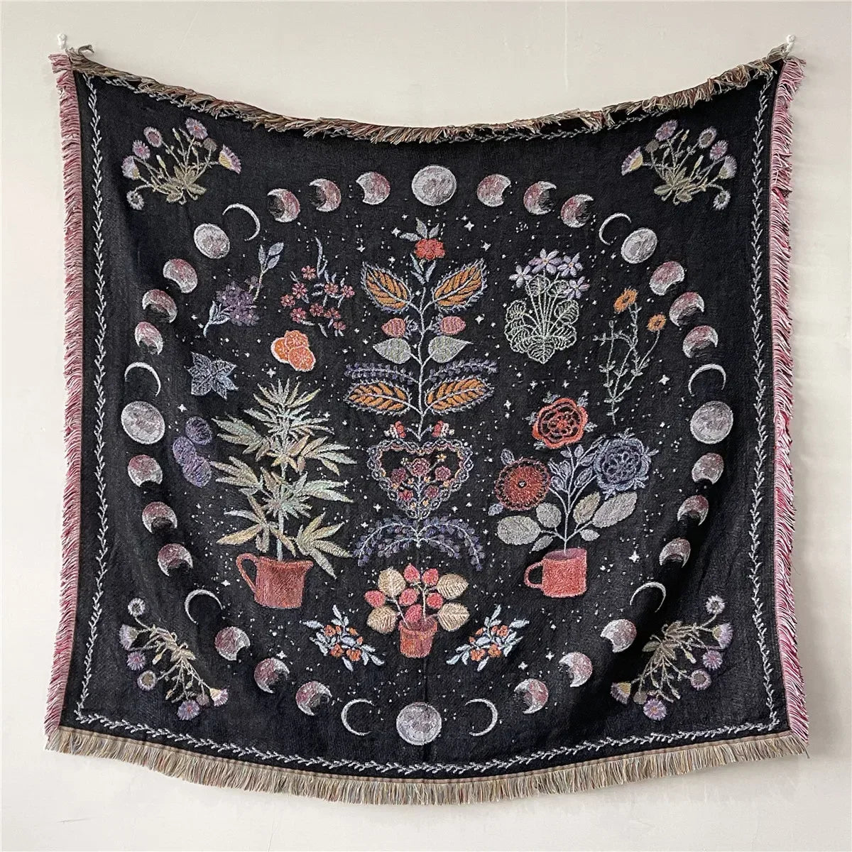 A dark throw blanket featuring geometric and bohemian patterns with various floral and crescent moon motifs.