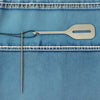 A stainless steel needle threader is shown against a blue denim fabric with stitching.