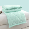 Light mint green quilted duvet folded on a white surface