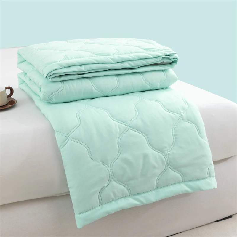 Light mint green quilted duvet folded on a white surface