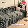 A grey sofa cover featuring a black and white herringbone pattern with tassel fringes.