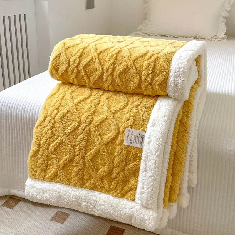 A thick yellow fleece blanket with white trim is folded on a white bed.