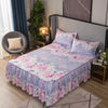 A bed featuring a purple and pink floral printed bed skirt on a bed with a dark headboard.