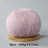 A ball of light pink mohair yarn resting on a wooden base.