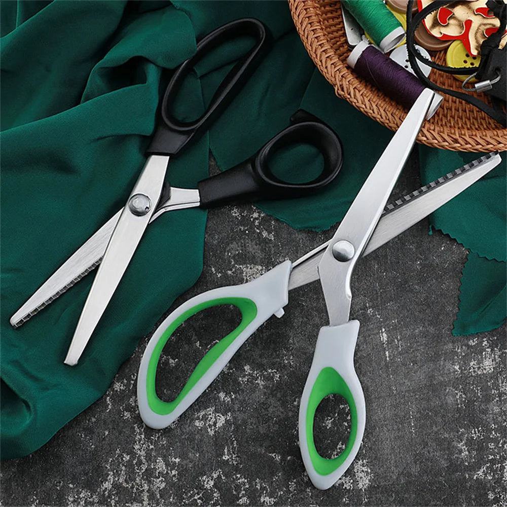 A pair of silver professional pinking shears with ergonomic grips resting on a dark green cloth.