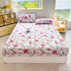 A white fitted bed sheet with a pink floral print is displayed on a bed in a bright room.