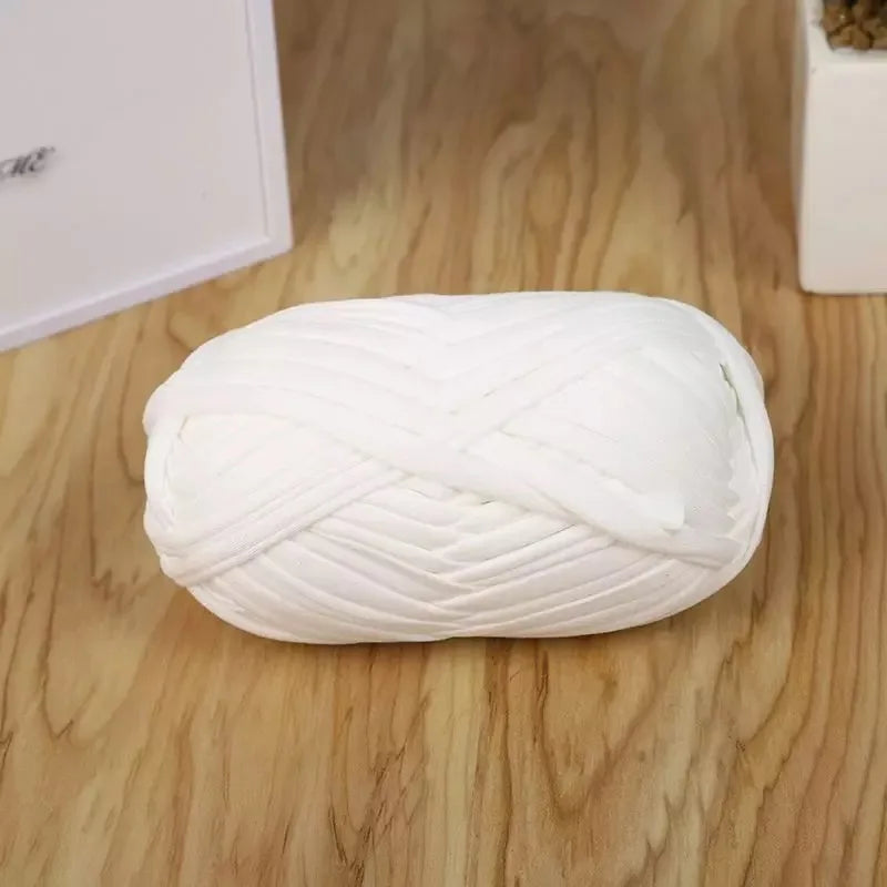 A ball of white flat thread yarn for crafting and sewing resting on a wooden surface.
