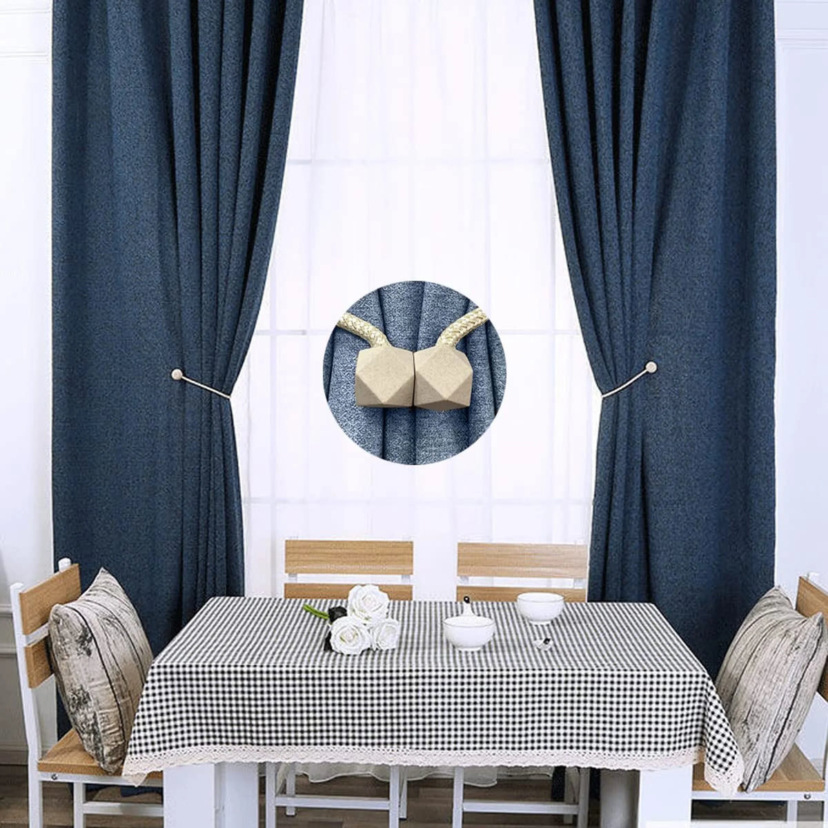 A table setting with a white tablecloth and dark blue curtains, featuring magnetic curtain tiebacks and decorative fabric.