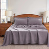 A bed dressed with a solid gray pure French linen bed sheet on a wooden bed frame.